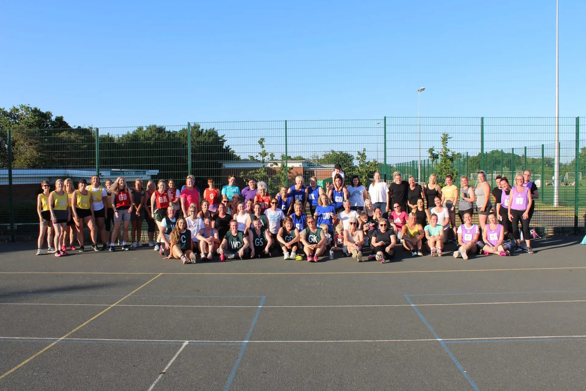 Image of a netball team in green bibs posing for a photo in a sports hall