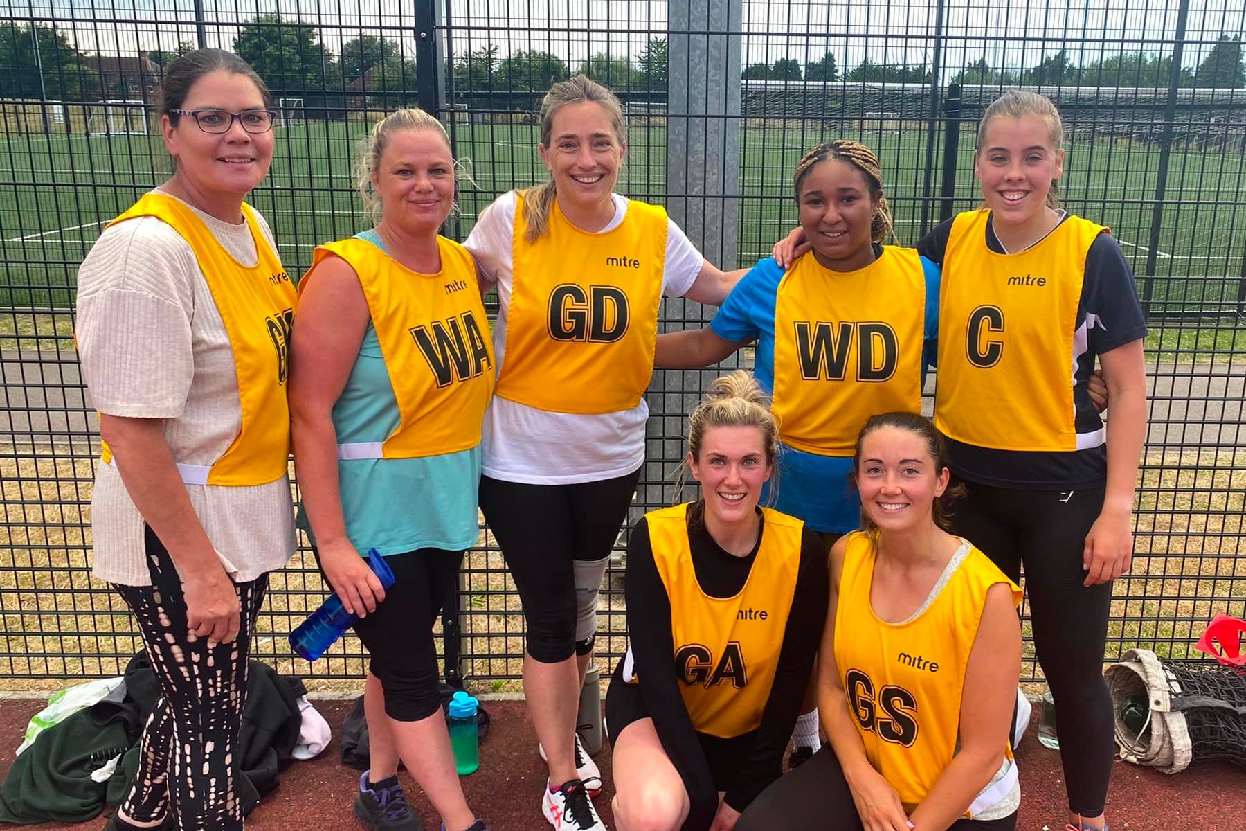 Image of a netball team in yellow bibs posing for a photo