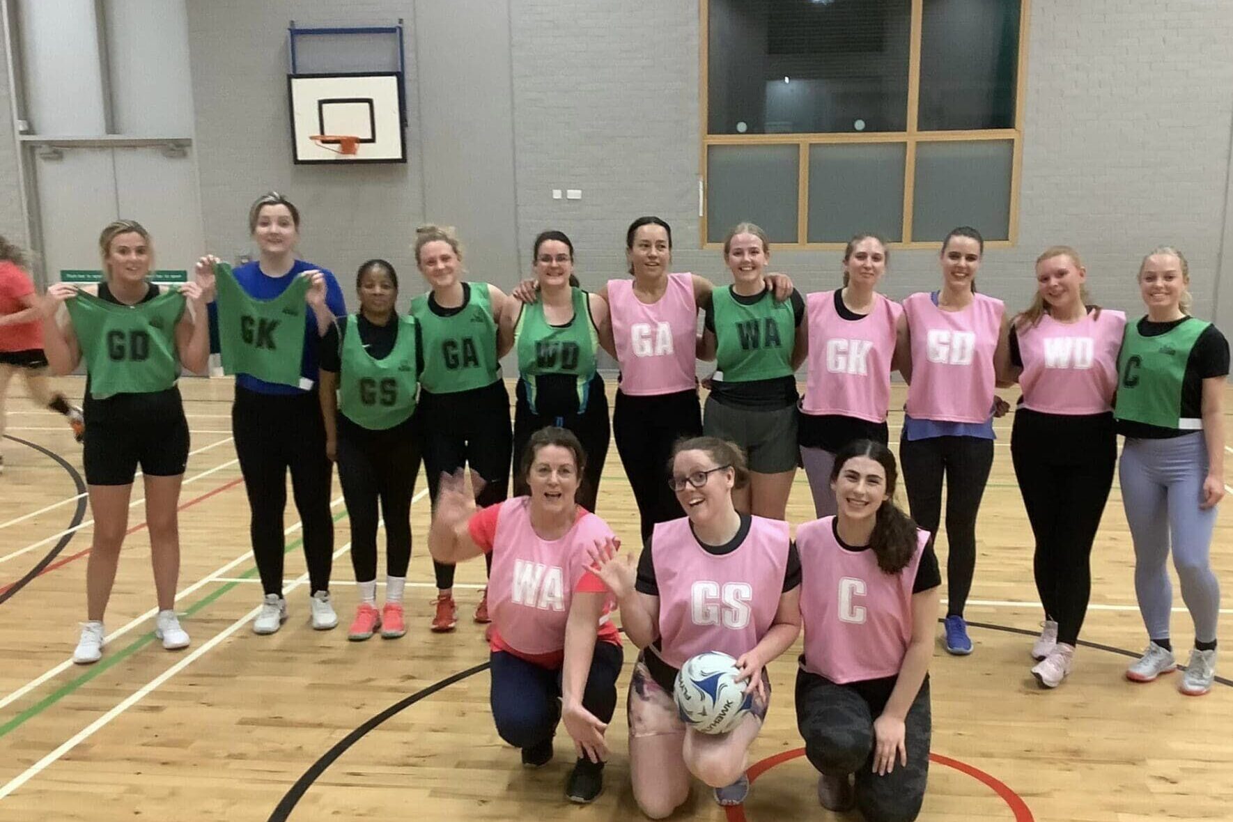 Image of a netball team in yellow bibs posing for a photo